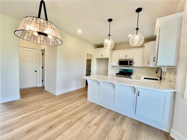7709 NE 106th Pl, Kansas City, MO 64157 - kitchen with stainless steel appliances, tasteful backsplash, light countertops, light wood-style floors, and a peninsula