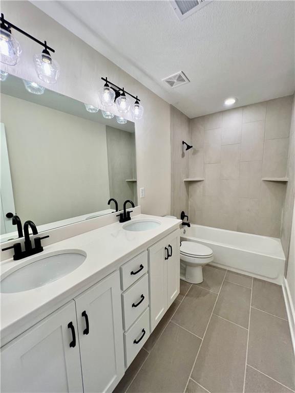 7709 NE 106th Pl, Kansas City, MO 64157 - full bath featuring double vanity, tile patterned floors, bathtub / shower combination, and a textured ceiling