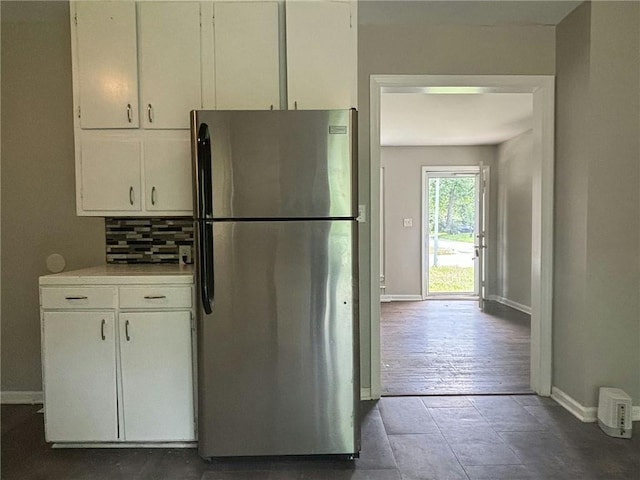 kitchen featuring dark hardwood / wood-style flooring, white cabinets, backsplash, and stainless steel refrigerator