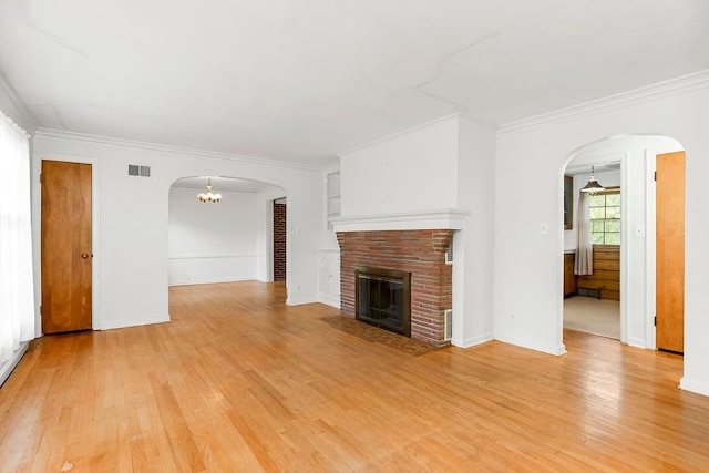 unfurnished living room with light wood-type flooring, crown molding, and a brick fireplace