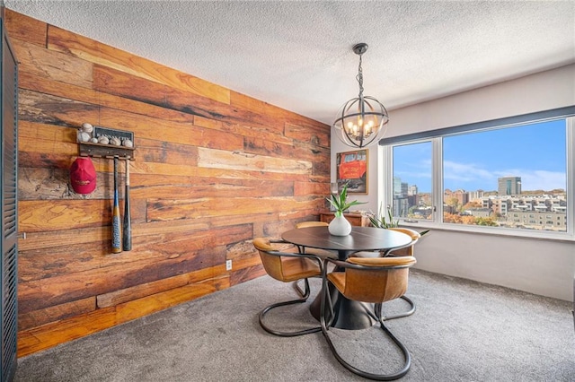 carpeted dining room featuring wood walls, a textured ceiling, and a chandelier