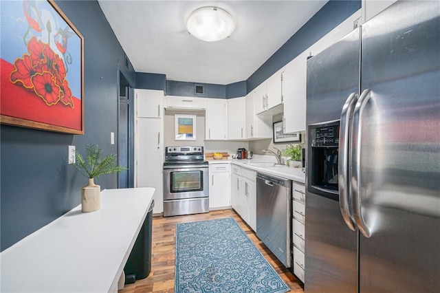 kitchen with sink, white cabinets, wood-type flooring, and appliances with stainless steel finishes