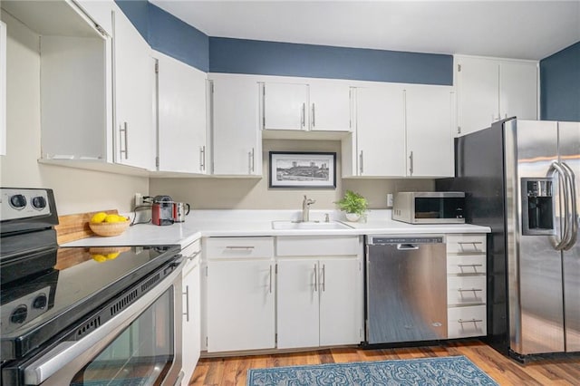 kitchen featuring white cabinetry, sink, light wood-type flooring, and appliances with stainless steel finishes