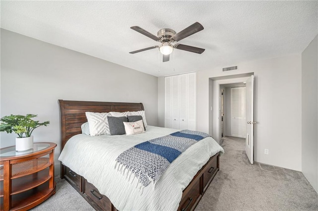 carpeted bedroom featuring a textured ceiling, a closet, and ceiling fan