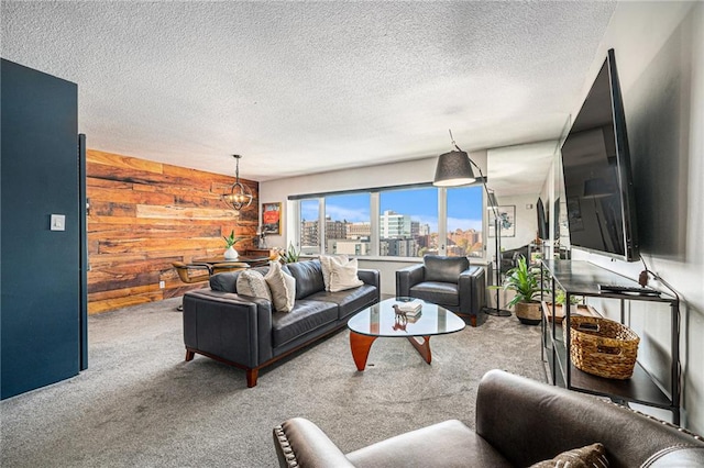 living room featuring carpet, a textured ceiling, a chandelier, and wooden walls