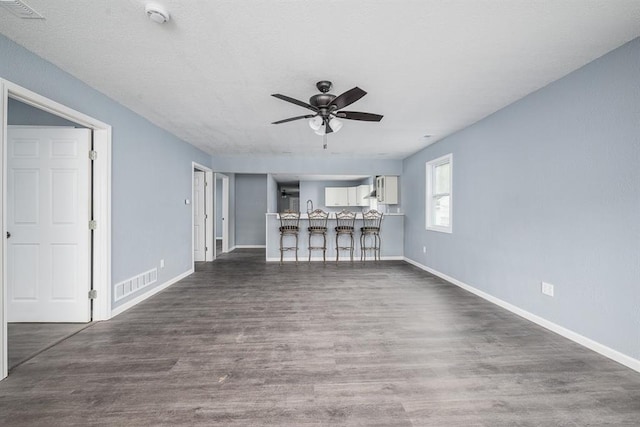 unfurnished living room featuring ceiling fan and dark hardwood / wood-style floors