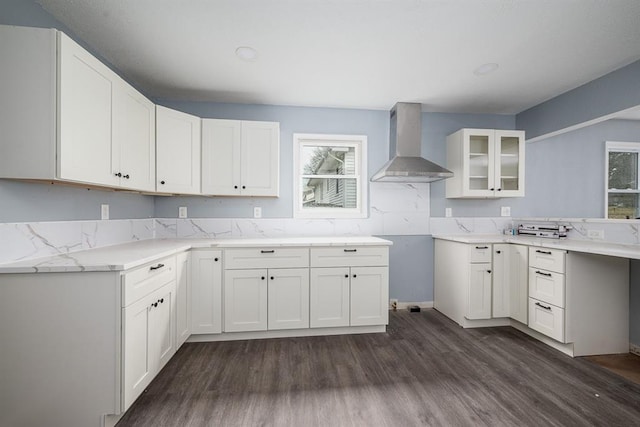 kitchen with white cabinets, wall chimney range hood, light stone counters, and dark hardwood / wood-style flooring