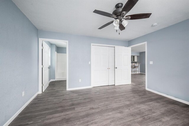 unfurnished bedroom with dark hardwood / wood-style flooring, a closet, and ceiling fan