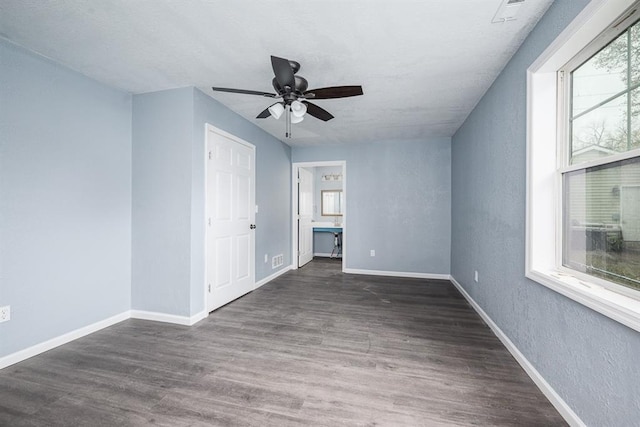 204 N 17th St, Leavenworth, KS 66048 - unfurnished bedroom with multiple windows, wood finished floors, baseboards, a textured wall, and a ceiling fan