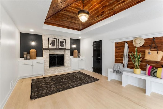 living area with baseboards, a tray ceiling, light wood-style flooring, a fireplace, and wooden ceiling