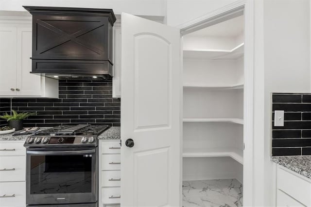 kitchen with marble finish floor, backsplash, white cabinetry, light stone countertops, and stainless steel range with gas stovetop