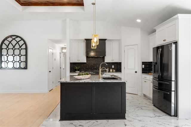 kitchen featuring light stone countertops, tasteful backsplash, marble finish floor, and black fridge