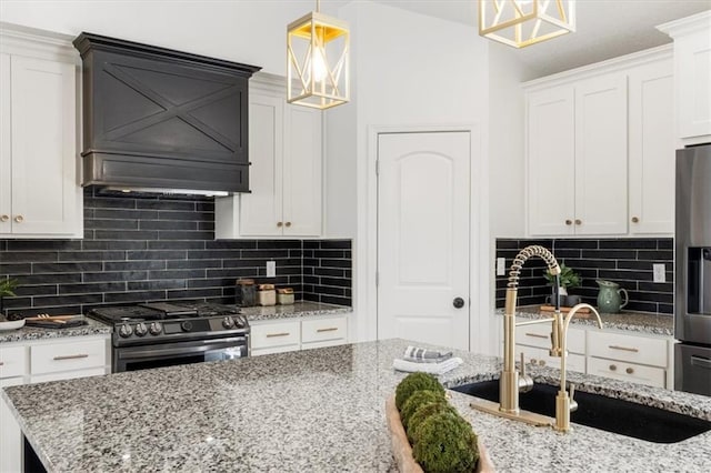 kitchen featuring light stone counters, a sink, stainless steel appliances, white cabinetry, and backsplash