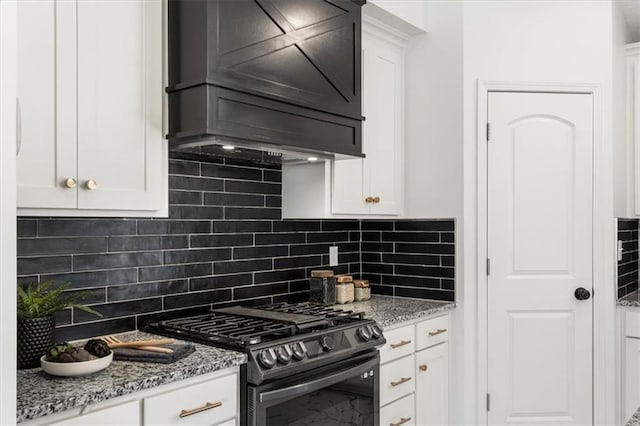 kitchen featuring decorative backsplash, custom range hood, white cabinets, and stainless steel gas range oven