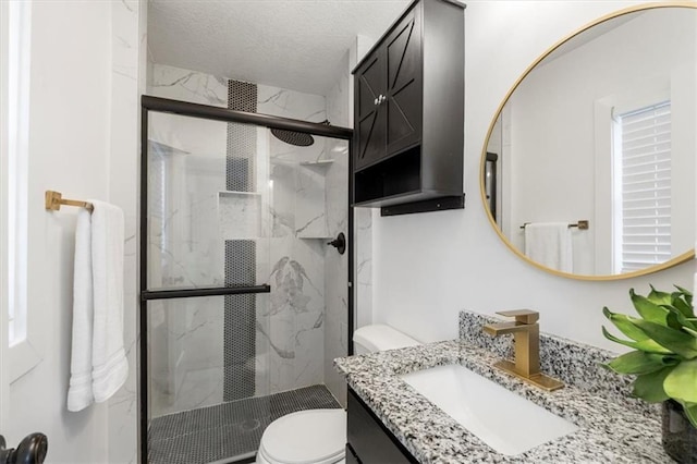 bathroom featuring vanity, toilet, a marble finish shower, and a textured ceiling