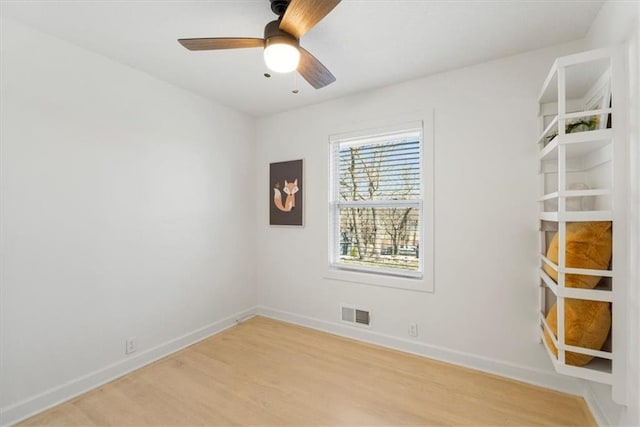 empty room featuring light wood finished floors, visible vents, ceiling fan, and baseboards