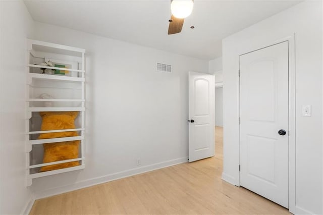 unfurnished bedroom with visible vents, baseboards, wood finished floors, and a ceiling fan