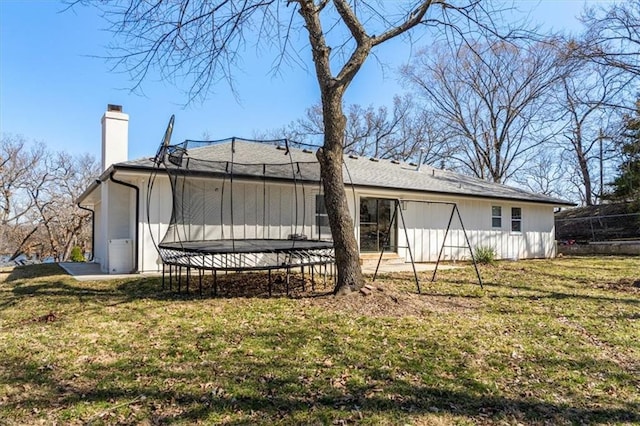 exterior space featuring a trampoline, a lawn, and a chimney