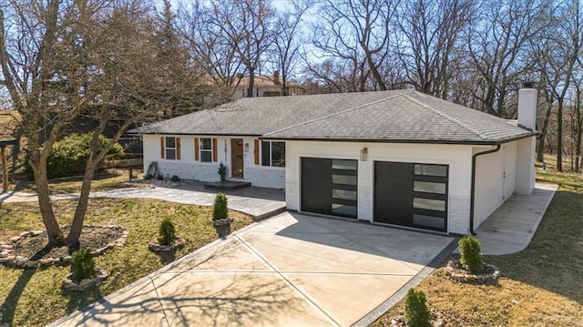 ranch-style house with a shingled roof, concrete driveway, a garage, and a chimney