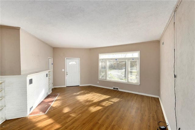 interior space with hardwood / wood-style flooring, ornamental molding, and a textured ceiling