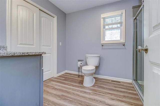 bathroom featuring hardwood / wood-style flooring, toilet, and walk in shower