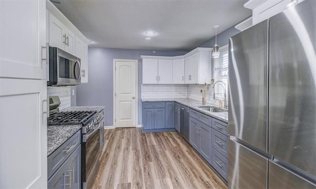 kitchen featuring decorative light fixtures, appliances with stainless steel finishes, sink, and white cabinets