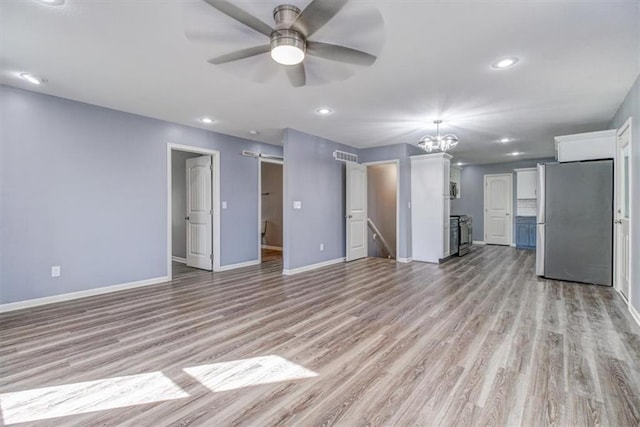 unfurnished living room featuring light wood-type flooring and ceiling fan with notable chandelier