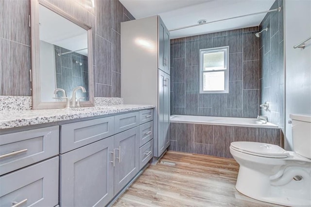 full bathroom featuring tiled shower / bath, hardwood / wood-style flooring, toilet, and vanity