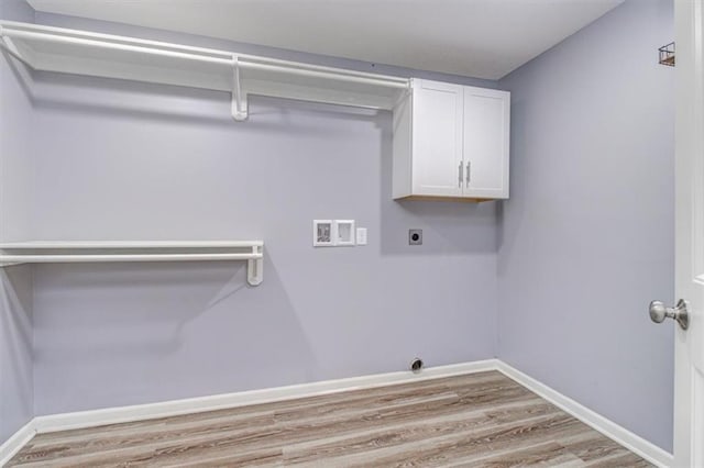 laundry room featuring hookup for an electric dryer, light hardwood / wood-style floors, washer hookup, and cabinets