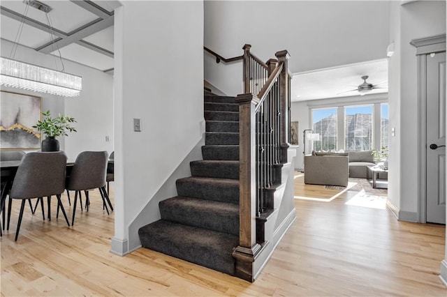 staircase with hardwood / wood-style flooring and ceiling fan with notable chandelier