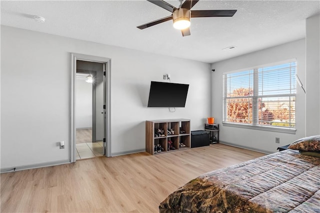 bedroom with ceiling fan, a textured ceiling, and light hardwood / wood-style flooring