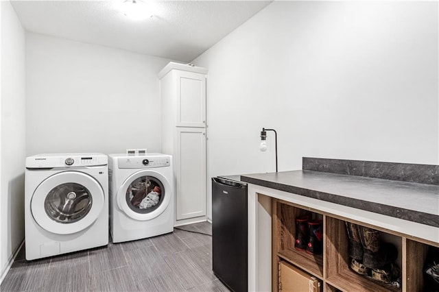 clothes washing area featuring washer and dryer and cabinets