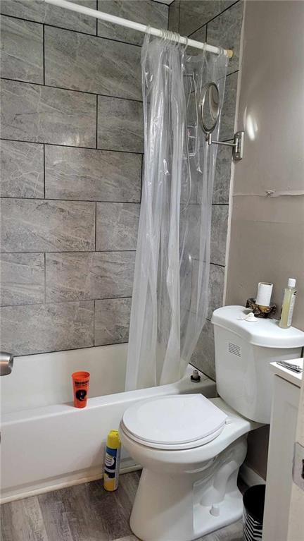 full bathroom featuring hardwood / wood-style floors, shower / bath combo with shower curtain, vanity, and toilet