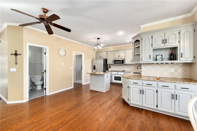 kitchen with white cabinets, light stone countertops, appliances with stainless steel finishes, a kitchen island, and dark hardwood / wood-style flooring