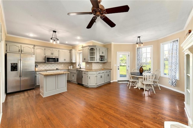 kitchen featuring decorative light fixtures, gray cabinets, appliances with stainless steel finishes, a kitchen island, and a sink