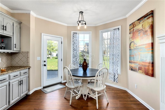 dining area featuring dark wood-style floors, a wealth of natural light, ornamental molding, and baseboards