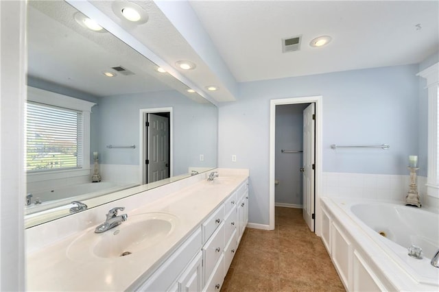 bathroom with a garden tub, visible vents, and a sink