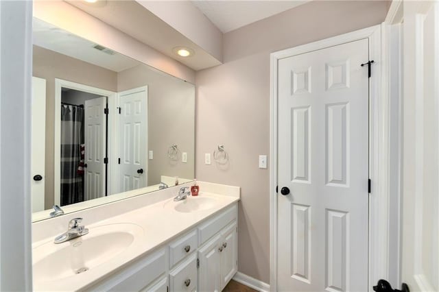 full bath with visible vents, a sink, baseboards, and double vanity