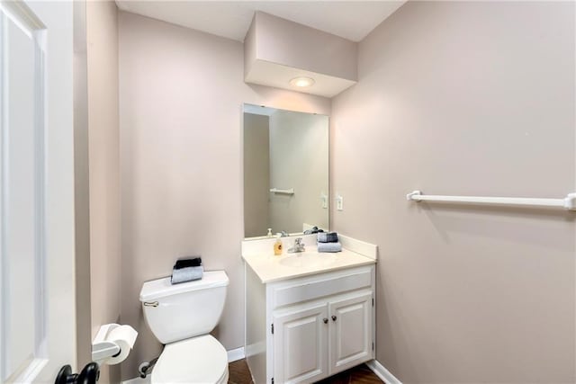 bathroom featuring toilet, vanity, and baseboards