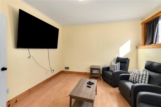 living area featuring visible vents, ornamental molding, light wood-style flooring, and baseboards