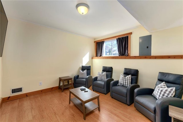 living room with baseboards, light wood-type flooring, visible vents, and electric panel