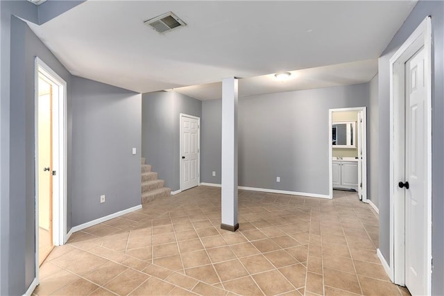 below grade area featuring stairs, light tile patterned floors, visible vents, and baseboards