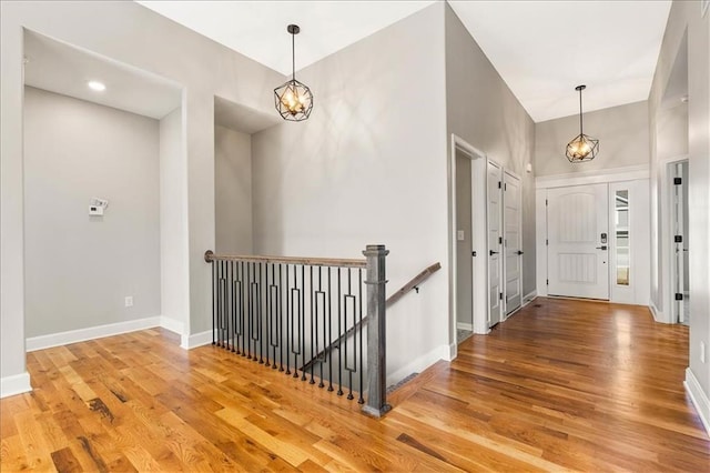 foyer with a chandelier, light wood finished floors, and baseboards