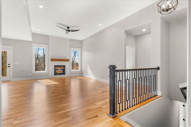 living room with light hardwood / wood-style flooring, ceiling fan with notable chandelier, and a fireplace