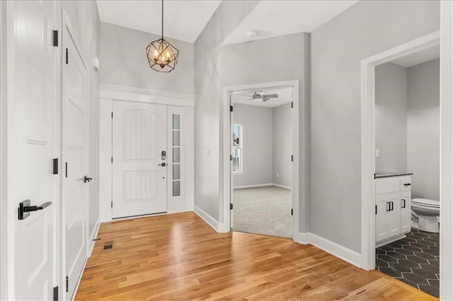 foyer with wood-type flooring and ceiling fan with notable chandelier