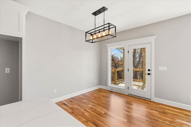 unfurnished dining area with a chandelier and light wood-type flooring