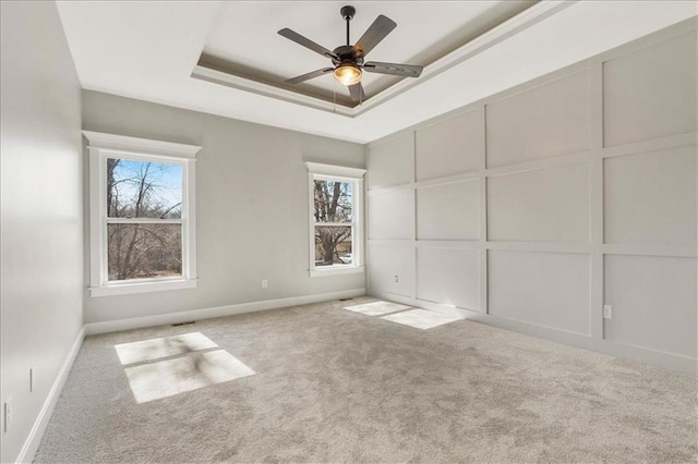 unfurnished room featuring ceiling fan, a tray ceiling, and light colored carpet