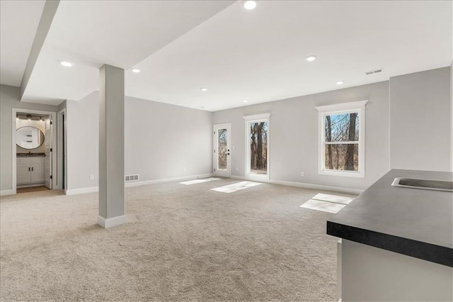 unfurnished living room featuring sink and light carpet