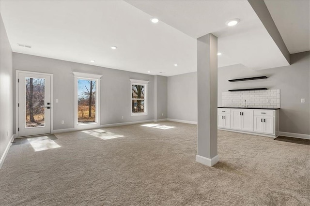 unfurnished living room with light carpet and indoor bar