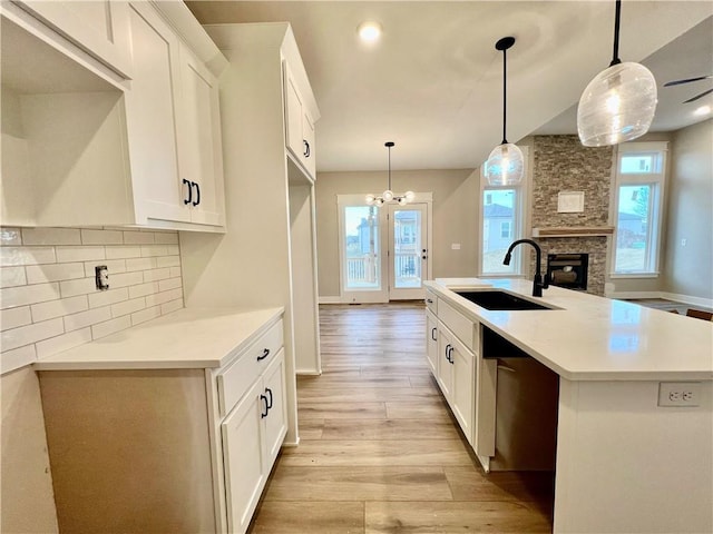 kitchen with a sink, white cabinetry, tasteful backsplash, and light wood finished floors